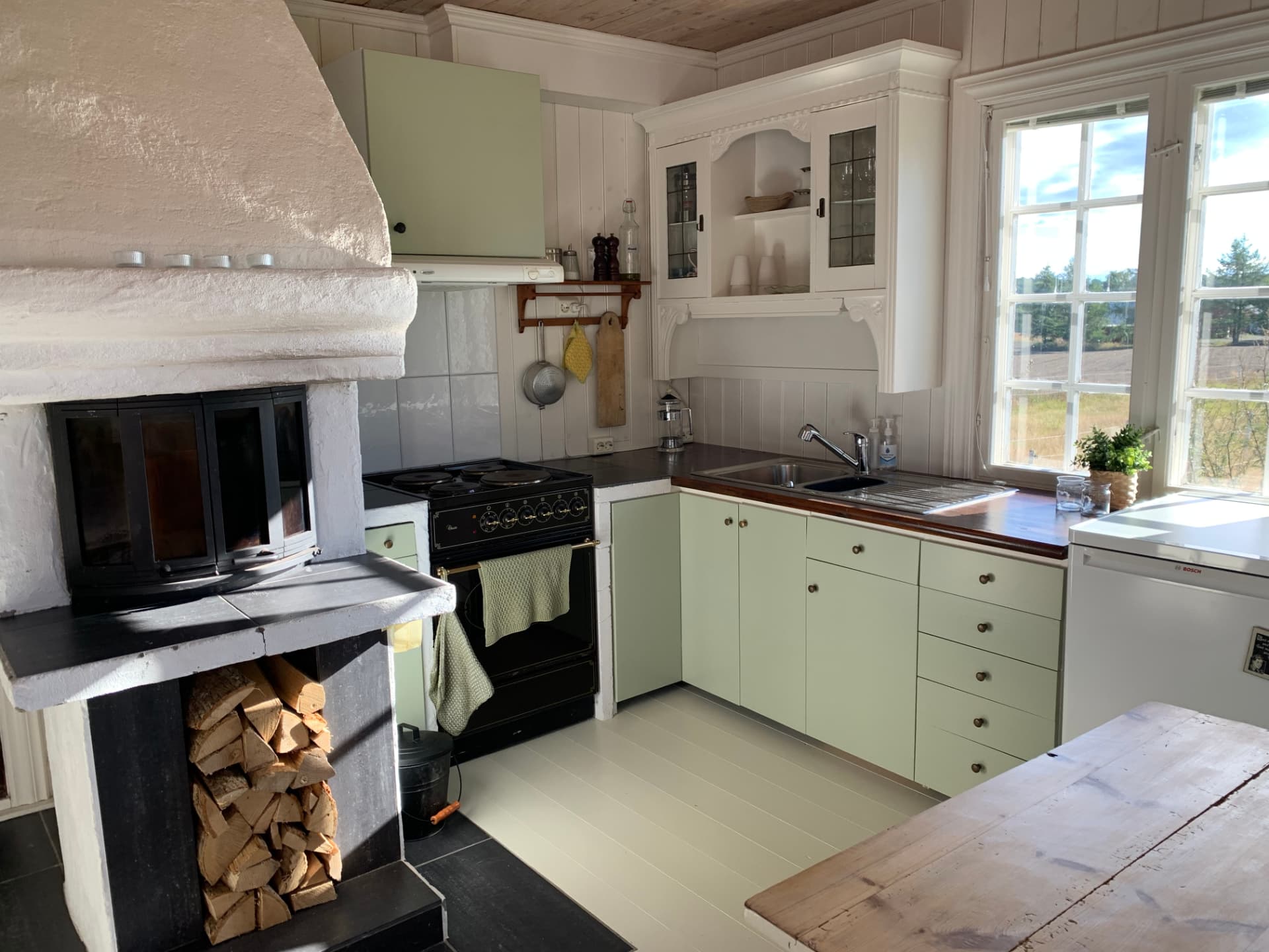 Kitchen with a wood-burning stove and pale green cabinets