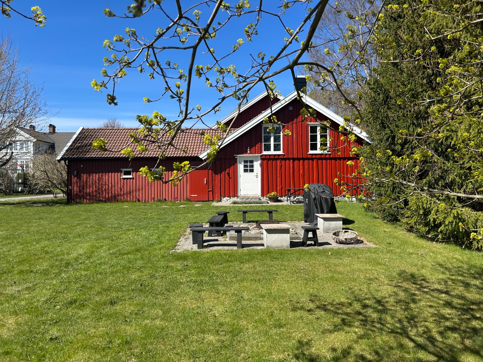 The red house with the fire pit and benches
