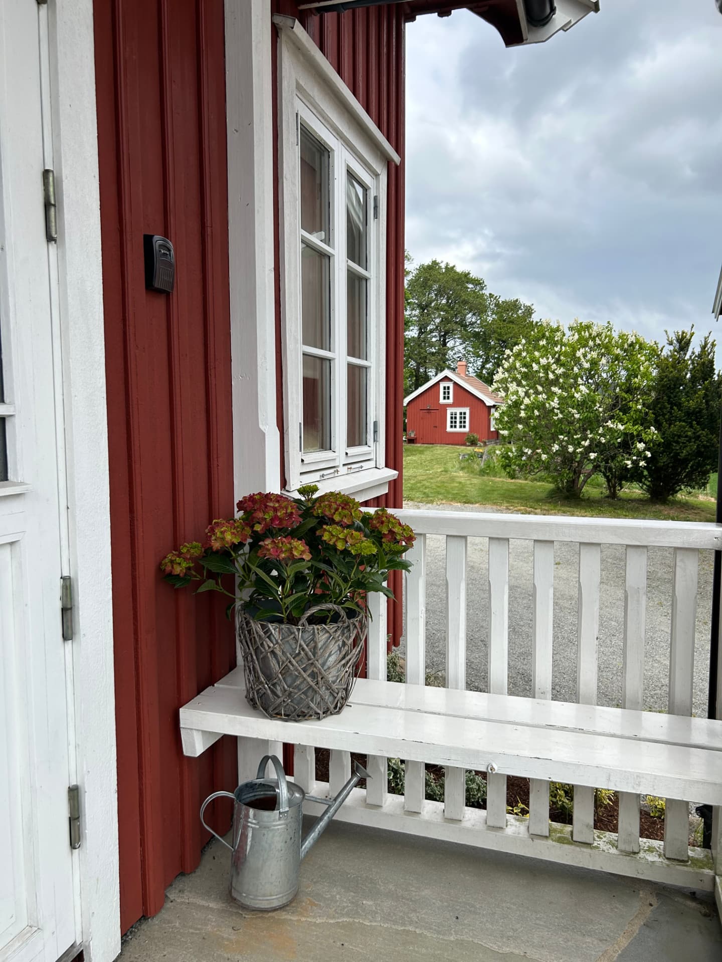 Porch with hydrangeas and a view towards a red house